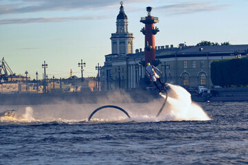 A man flies and circles over the water on a flyboard in the city river. Sportsman is engaged in...