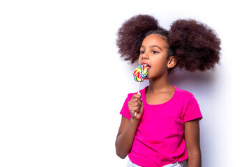 Cute multiracial small girl smiling lollipop in hand on background. Girl afro, lollipops. Smile...