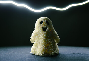 A toy smiling ghost stands in the semi-darkness and a strip of light above it