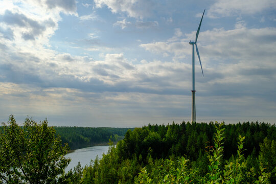 This is a former shale quarry with azure water and picturesque hills. Unlike the Narva shale settling ponds. A dark autumn day. Estonia, Aidu quarry. A tall wind turbine in the distance