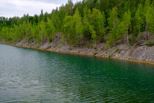 This is a former shale quarry with azure water and picturesque hills. Unlike the Narva shale settling ponds. A dark autumn day. Estonia, Aidu quarry.