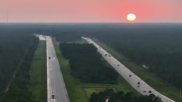 High angle view of wide congested american highway with many driving cars and trucks at sunset. Concept of interstate transportation system