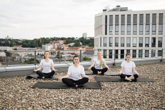 Women exercising lotus pose with gyan mudra on rooftop