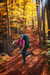Fototapeta premium Happy girl tourist rejoices in autumn on a hike in the mountains. Autumn trekking in the mountains. Recreation in the fresh air.