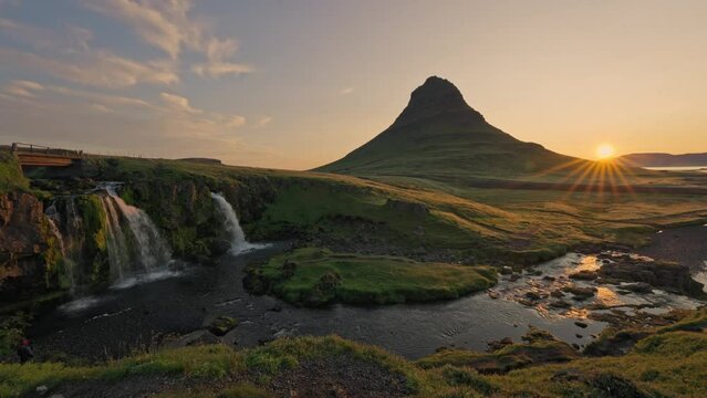 Sunrise over volcanic Kirkjufell mountain with waterfall flowing in summer at Iceland