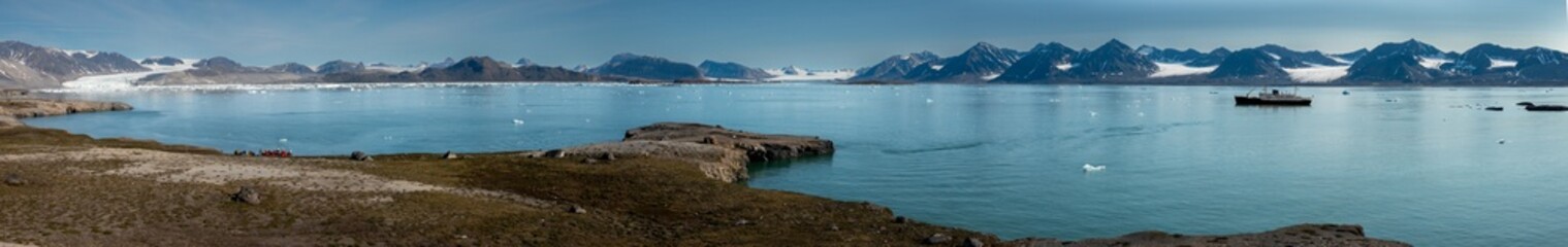 Landing on the shores of the spectacular Kongsfjorden, Spitsbergen, Svalbard, Norway. In the background on the left, the iconic three crown mountain (Tree Kroner) peaks