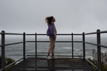 Young woman enjoying stormy weather as seaside - 646543450