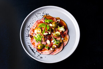 Beef tongue with sauce and vegetables on a white plate