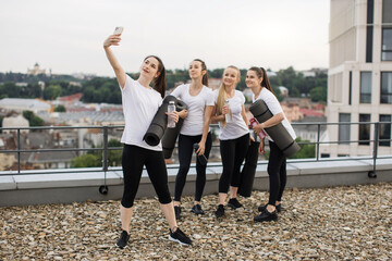 Yoga practitioners taking selfie on phone on roof terrace