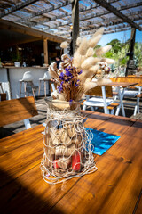 Small glass vase, filled with dried flowers and pluto wine corks, tied in fishing net, used as...
