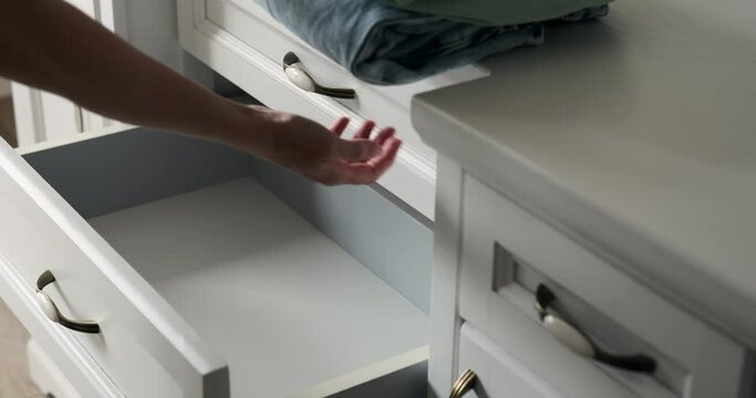 With a gentle touch, a woman meticulously arranges belongings within a dresser drawer. Her attentive demeanor exemplifies the art of tidying up, as she curates the contents with care.