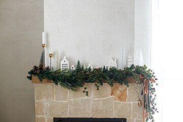 Stylish decorated christmas fireplace. Modern christmas trees, houses, pine cones and spruce...