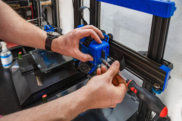 Close-up of technician's hands doing maintenance on 3D printer.