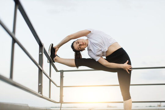 Adult person using handrail for side-bend stretch at sunset