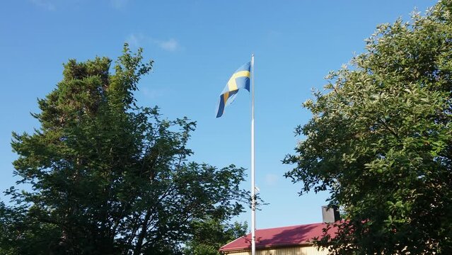 The Swedish flag flutters against a blue sky