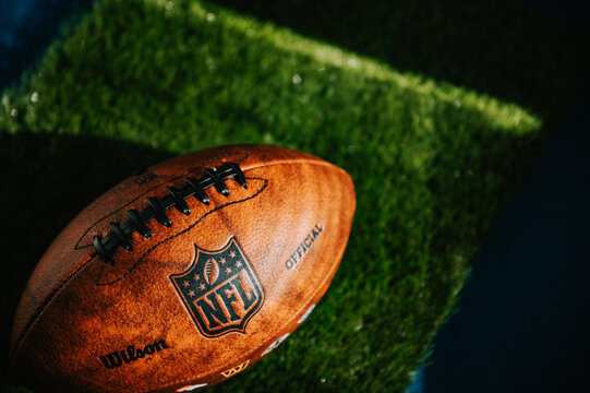 NEW YORK, USA, SEPTEMBER 11, 2023: NFL's Trademark: Leather Ball and Iconic Logo. Green Grass in background, black edit space, national football league official Wilson ball