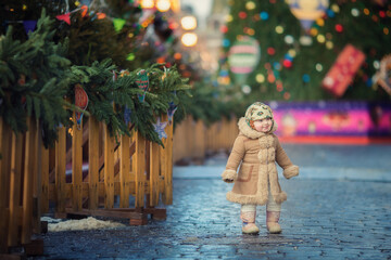 Little russian girl wearing shawl and fur coat with bagels on christmas market 