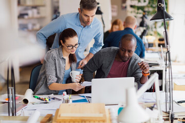 Diverse group of designers working on a laptop in a startup company office