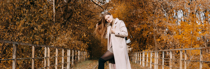 beautiful long-haired woman walks through the autumn streets. Railway, autumn, woman in a coat.