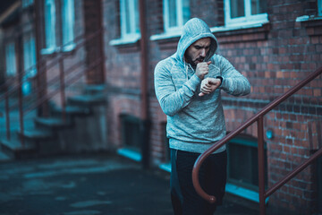 Young man looking at the time while getting ready to run in the city