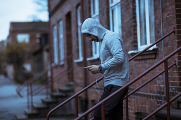 Young man using a smartphone and getting ready to go exercise and workout at night during winter and snow in the city