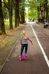 Little girl rollerskating in the park.