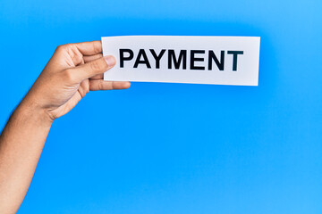 Hand of caucasian man holding paper with payment word over isolated blue background