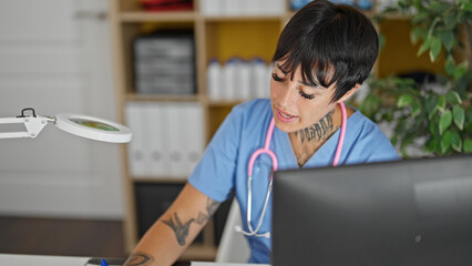 Young beautiful hispanic woman doctor using computer taking notes at clinic