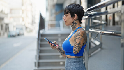 Hispanic woman with amputee arm using smartphone with serious expression at street