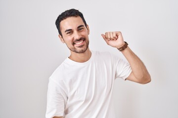 Handsome hispanic man standing over white background dancing happy and cheerful, smiling moving casual and confident listening to music