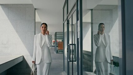 Woman manager consulting telephone walking office corridor. Lady boss calling