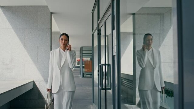 Woman manager consulting telephone walking office corridor. Lady boss calling