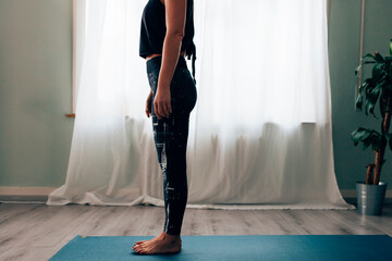 silhouette of woman in sportswear standing on mat ready to do exercises
