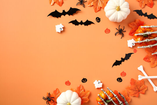Halloween flat lay composition with pumpkins, bats, spider maple leaves on pastel orange background. Flat lay, top view, copy space.