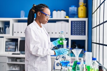 African american woman scientist pouring liquid on test tube at laboratory