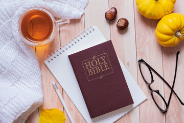 Holy bible and autumn cozy top view on wooden background. Bible study autumn concept
