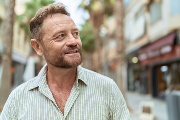 Middle age man smiling confident looking to the side at street