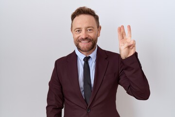 Middle age business man with beard wearing suit and tie showing and pointing up with fingers number three while smiling confident and happy.