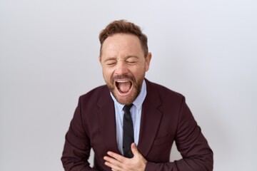 Middle age business man with beard wearing suit and tie smiling and laughing hard out loud because funny crazy joke with hands on body.