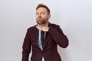 Middle age business man with beard wearing suit and tie cutting throat with hand as knife, threaten aggression with furious violence