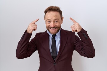 Middle age business man with beard wearing suit and tie smiling pointing to head with both hands finger, great idea or thought, good memory