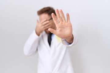 Middle age doctor man with beard wearing white coat covering eyes with hands and doing stop gesture with sad and fear expression. embarrassed and negative concept.