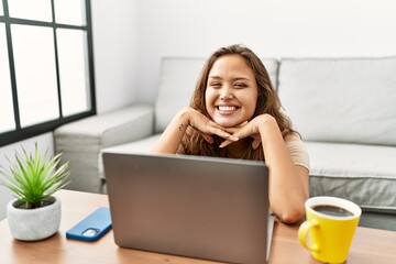 Young beautiful hispanic woman using laptop sitting on floor at home