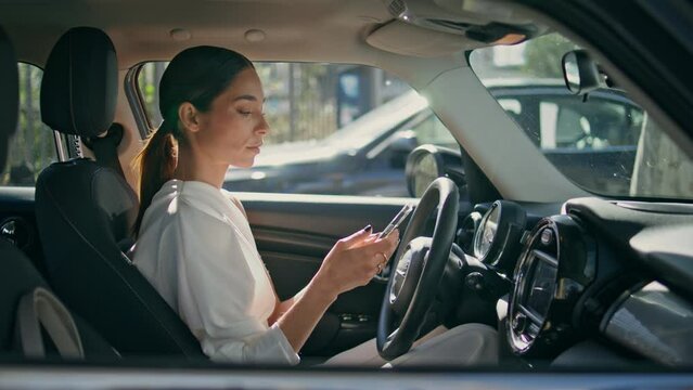 Luxurious driver looking phone sitting vip auto closeup. Woman working cellphone