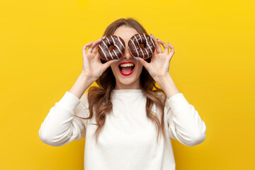 young cute girl with sweet donuts rejoice on yellow isolated background, woman with pastry looks...