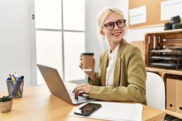 Young blonde woman business worker using laptop drinking coffee at office