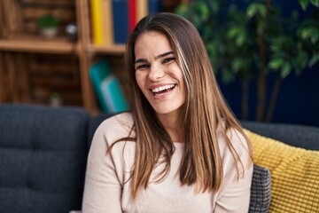 Young beautiful hispanic woman smiling confident sitting on sofa at home