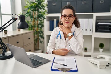 Young hispanic woman wearing doctor uniform and stethoscope cutting throat with hand as knife, threaten aggression with furious violence