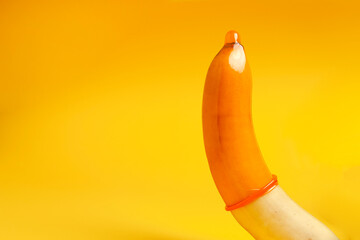 safe sex concept, banana with condom on yellow background, healthy potency