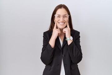 Beautiful brunette woman wearing business jacket and glasses smiling with open mouth, fingers pointing and forcing cheerful smile
